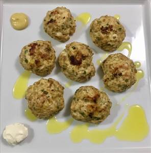Almôndegas de frango grelhadas servidas num prato branco com azeite