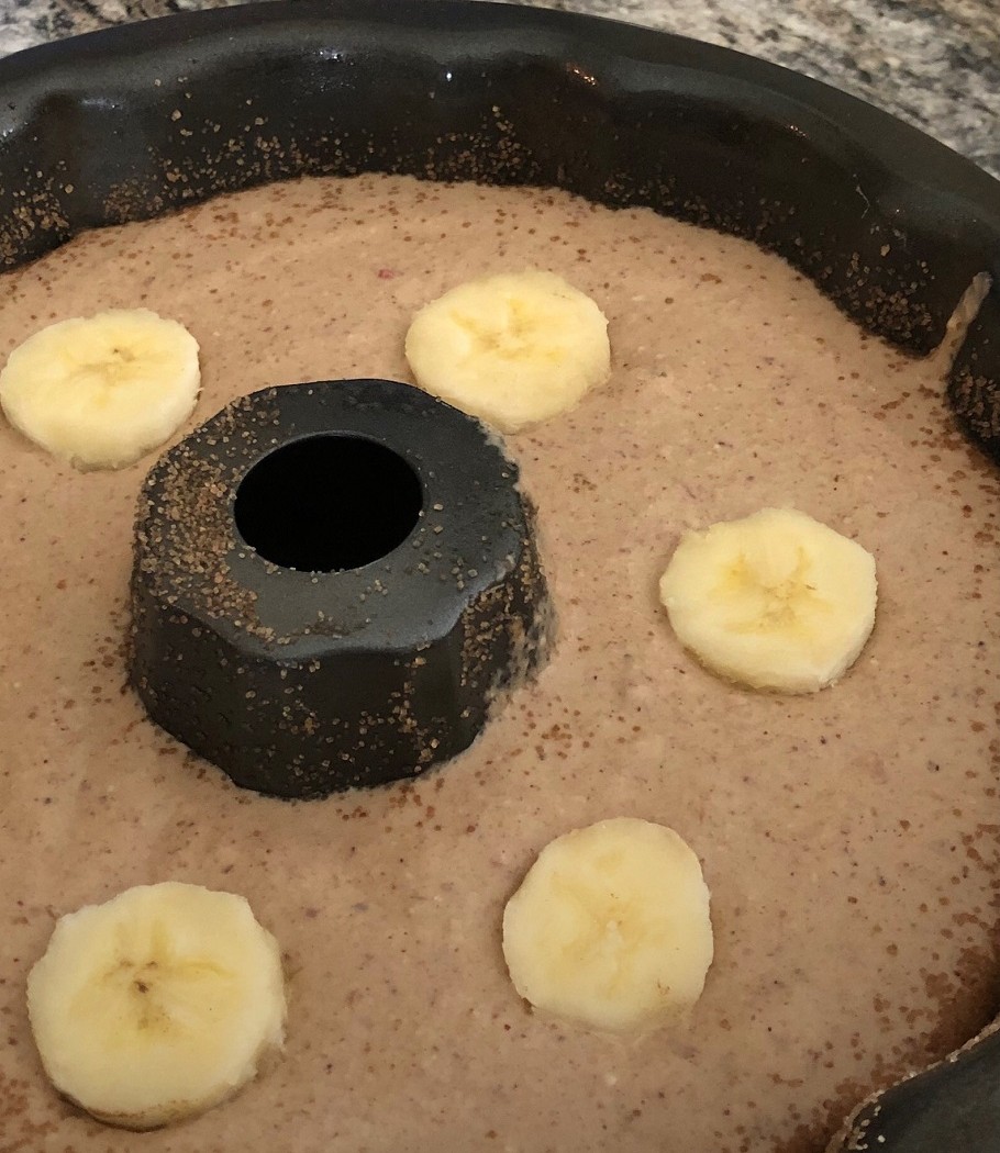 Massa do bolo na forma com furo central, decorada com rodelas de banana e canela
