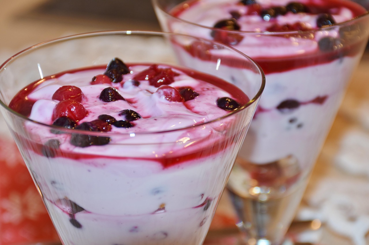 Sobremesa cremosa com calda e frutas vermelhas em taças de vidro