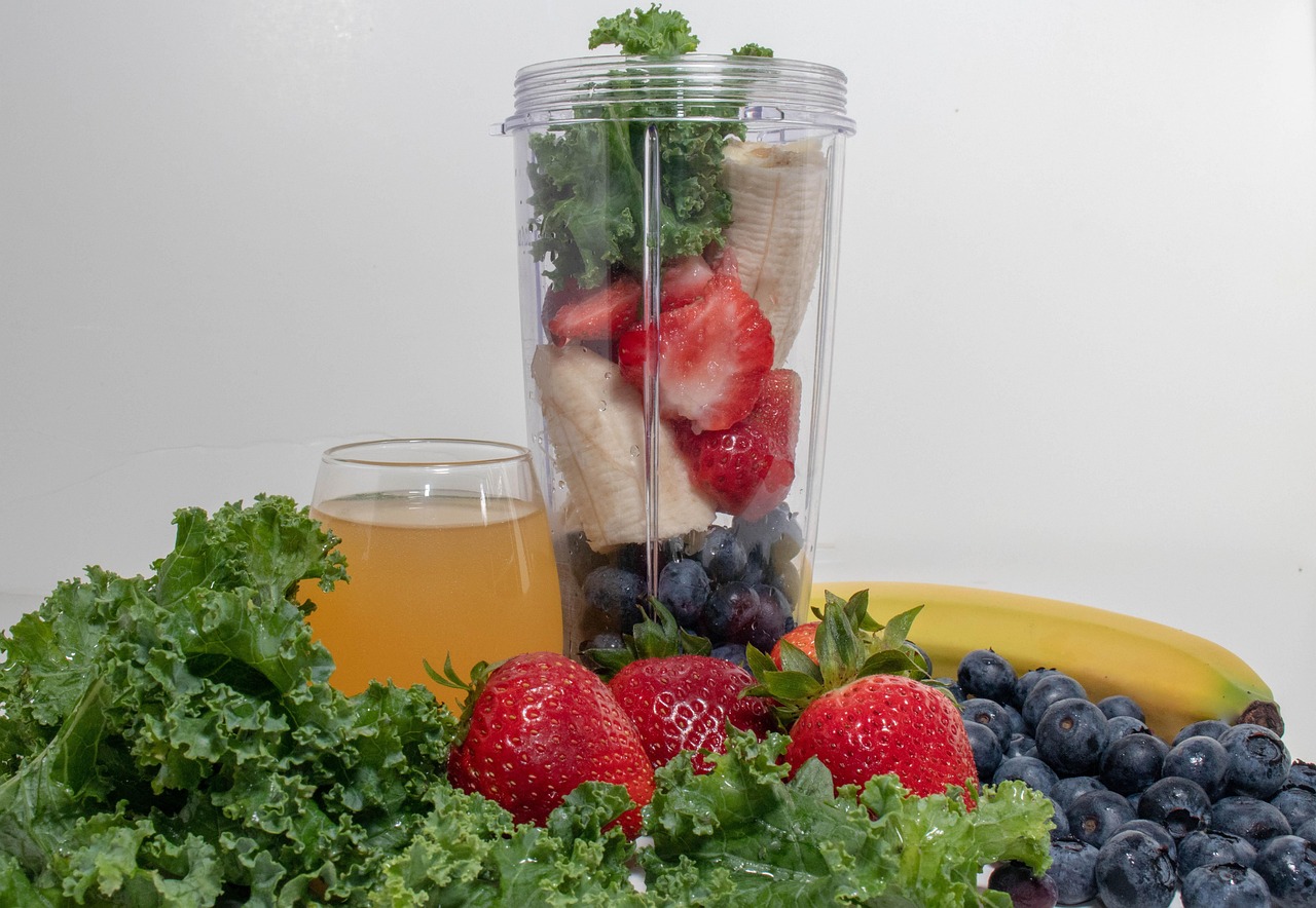 Banana, morangos, mirtilos e couve dentro do copo do liquidificador, prontos para bater