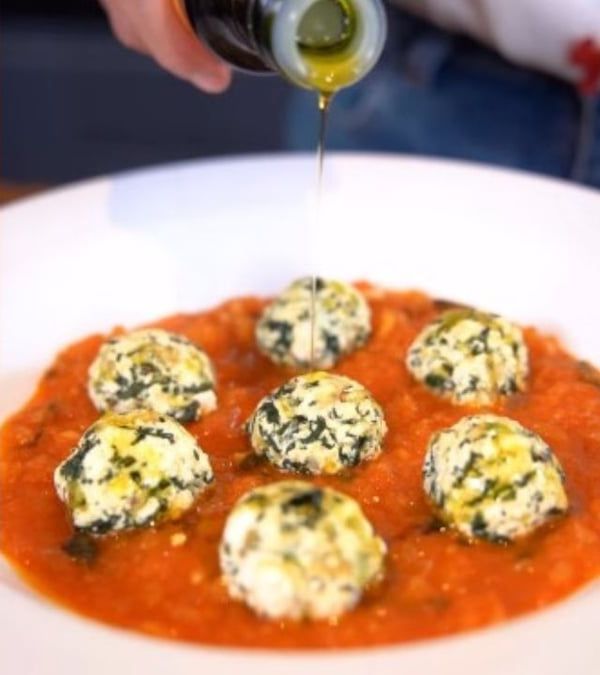 Nhoque de ricota servido em molho de tomate, com um fio de azeite por cima