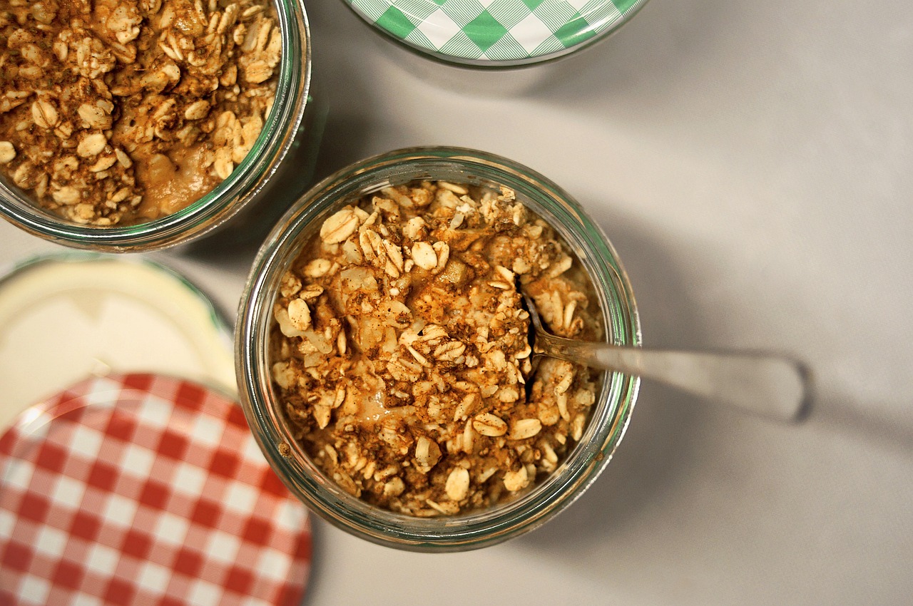 Potinhos de overnight oats vistos de cima, com colher, mostrando a textura cremosa da aveia