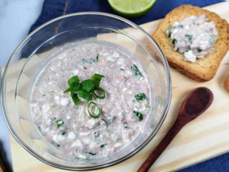 Close do patê de atum fit cremoso dentro de uma tigela de vidro, decorado com cebolinha picada