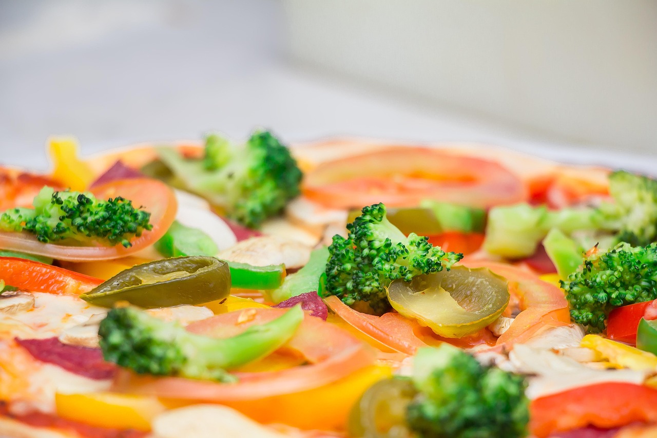 Close-up de pizza coberta com brócolis, pimentão e tomate