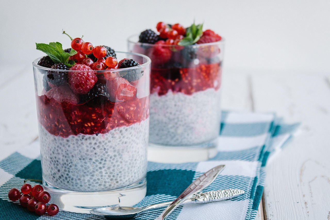 Pudim de chia servido em copos com camada de geleia e frutas vermelhas por cima
