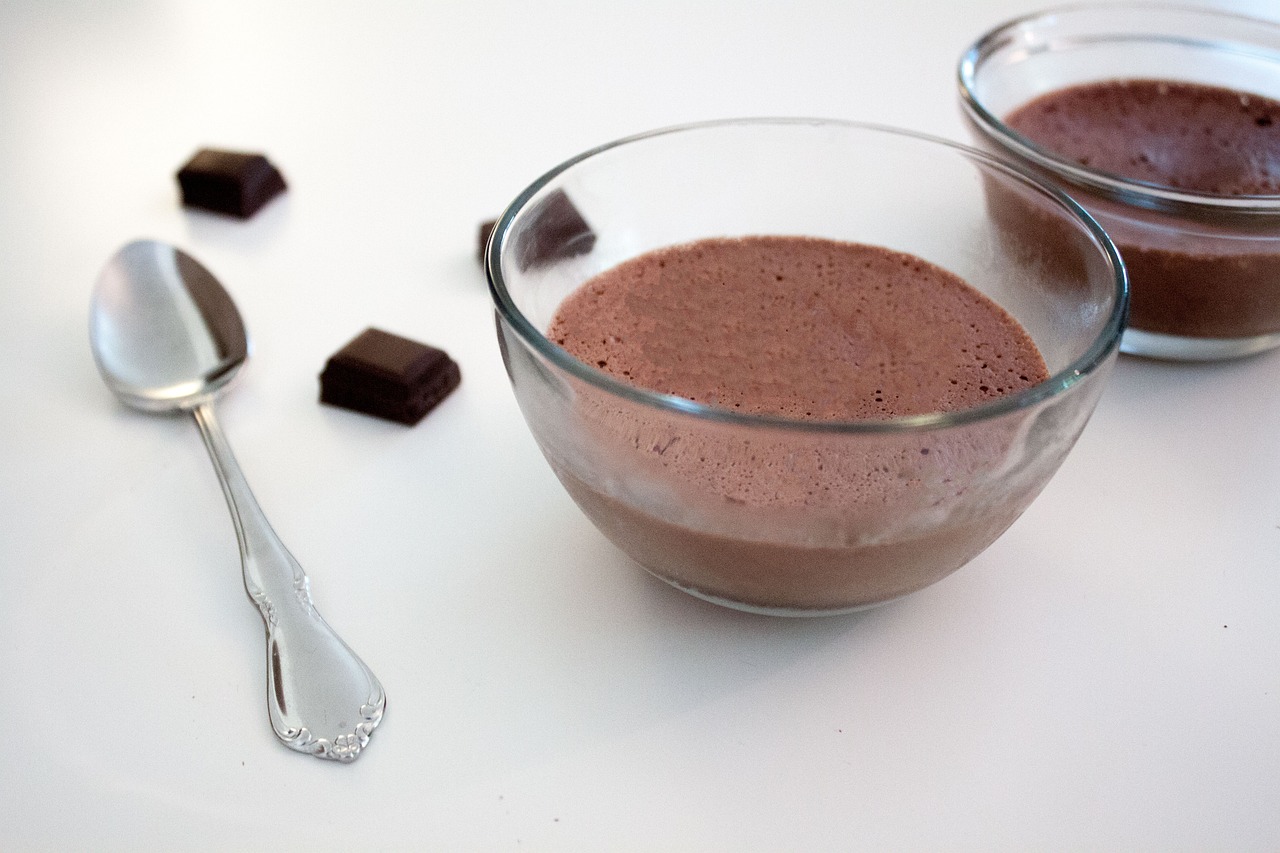 Pudim de chocolate servido em potinhos de vidro, com colher ao lado