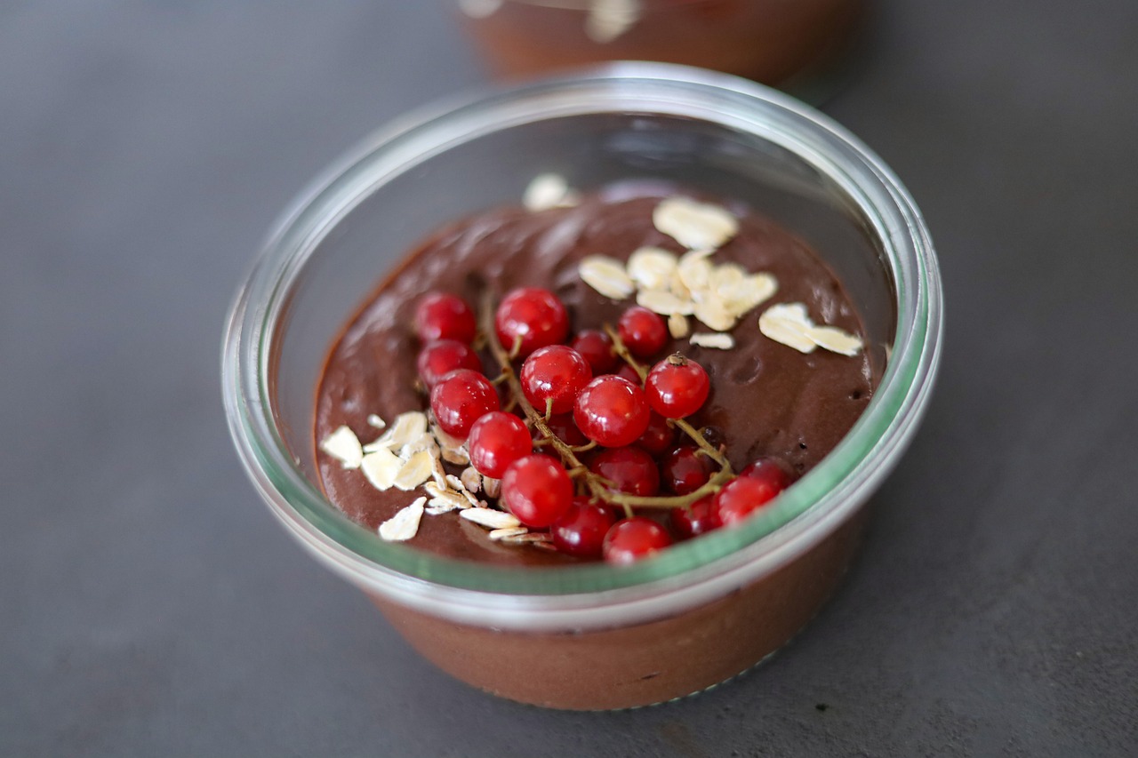 Sobremesa cremosa de chocolate servida em potinho individual, com frutas vermelhas