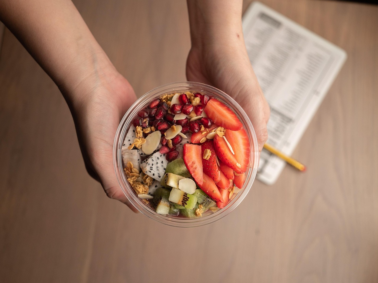 Tigela de açaí fit sendo servida à mesa, decorada com rodelas de banana e granola