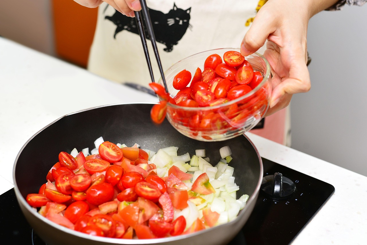 Cebola e tomate sendo refogados em frigideira, base do recheio