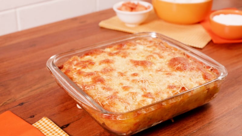 Torta de tapioca gratinada e dourada, servida num refratário quadrado de vidro